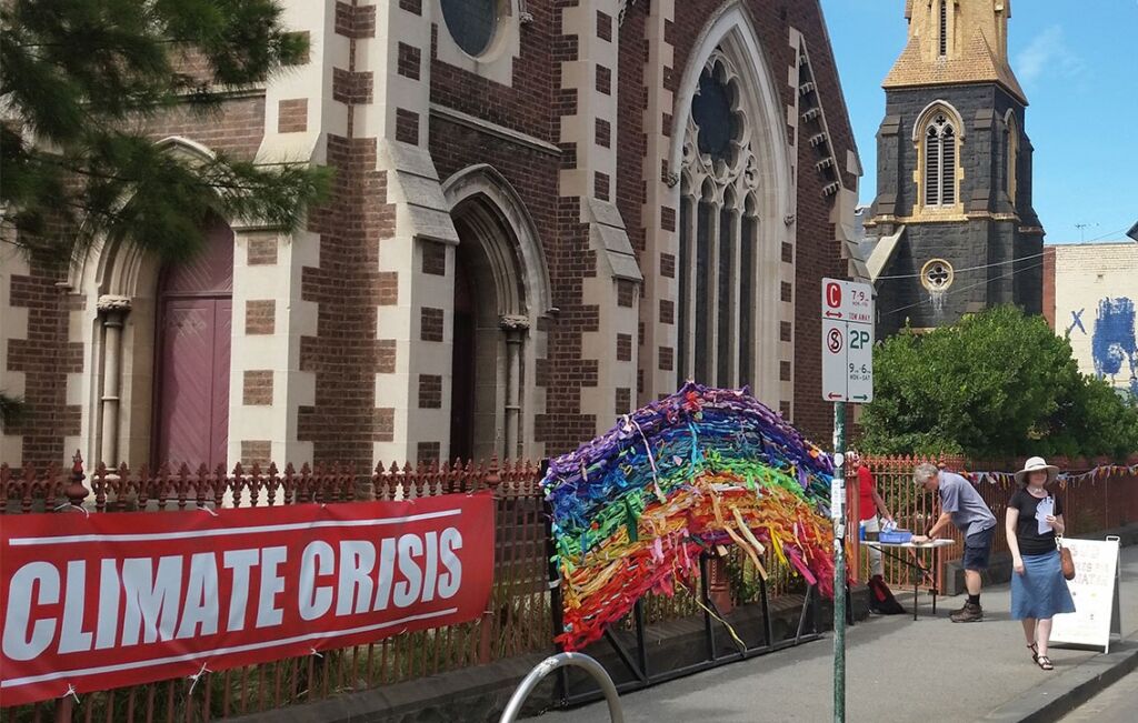 Street frontage of Brunswick Uniting Church with a banner on the front fence with text 'climate crisis'