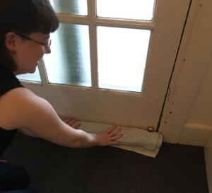 Person placing a rolled towel at the base of a closed door