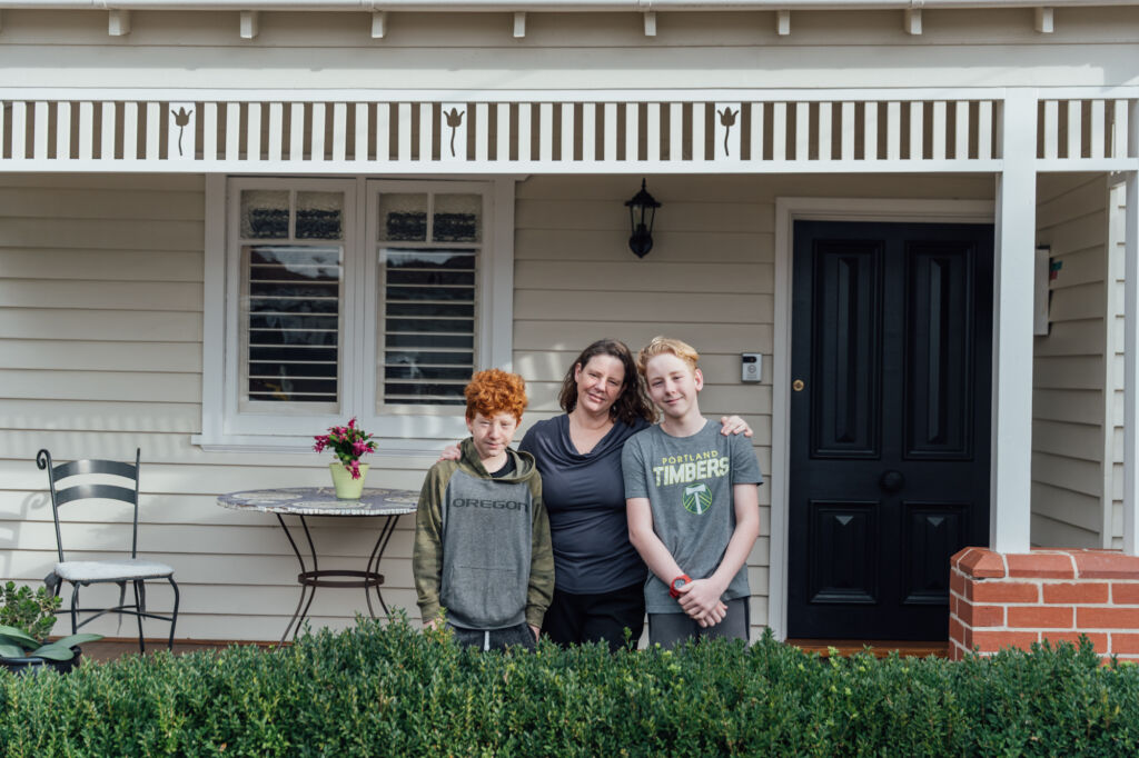 Katy and her sons standing in front of her home
